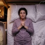 Overhead view of an exhausted new mother lying awake beside her sleeping baby struggling with postpartum OCD intrusive thoughts at night